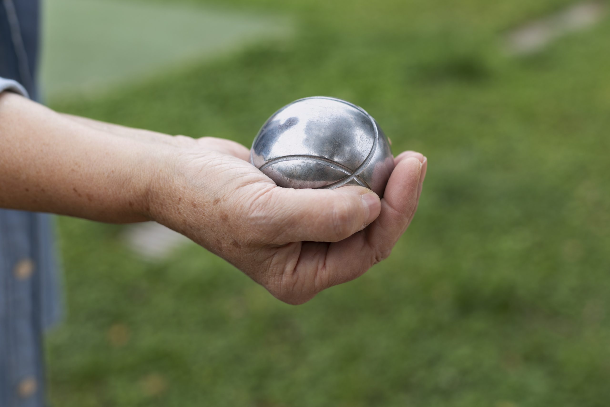Hand holding a pétanque boule, image from freepix